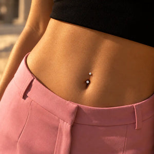 Model wearing a 14k gold prong-set curved barbell with 4mm clear gems in a belly button piercing