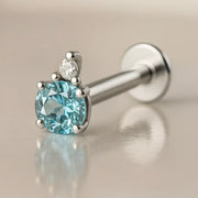 14k white gold aquamarine and diamond accent flat back labret on reflective surface, front angle view