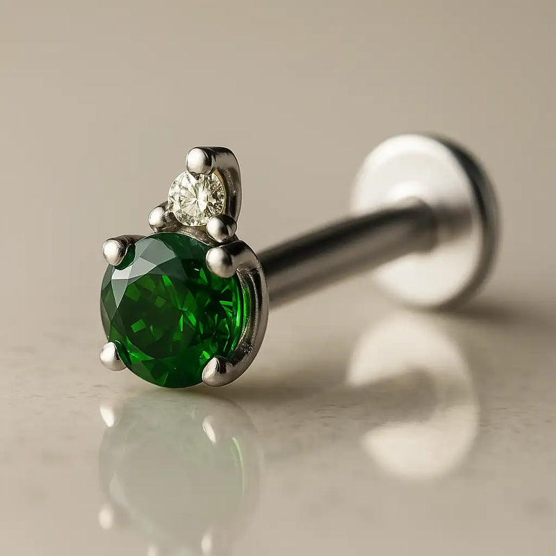 14k white gold emerald and diamond accent flat back labret, angled view showing silver-toned prong setting