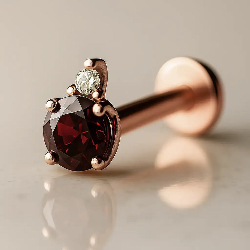 14k rose gold garnet and diamond flat back labret, angled view showing warm gold tones with deep red garnet