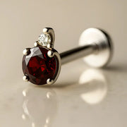 14k white gold garnet and diamond flat back labret, angled view highlighting prong-set deep red garnet