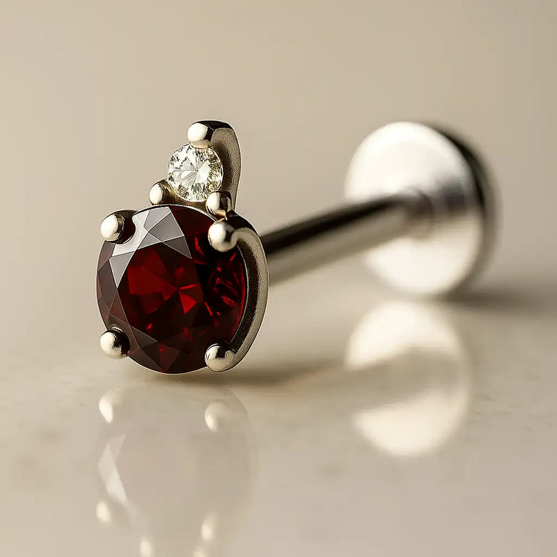 14k white gold garnet and diamond flat back labret, angled view highlighting prong-set deep red garnet
