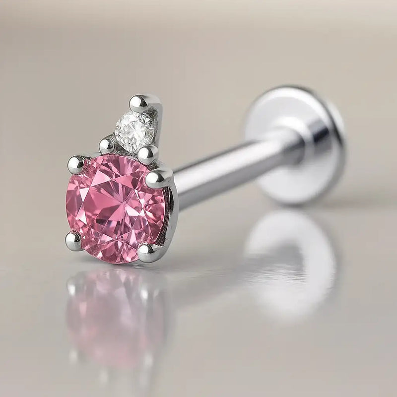 14k white gold flat back labret with pink tourmaline and diamond accent, angled side view on reflective surface