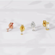 Flat lay of diamond baguette studs in 14K rose gold, yellow gold, and white gold on white fabric