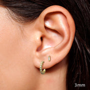 3mm 14K yellow gold baguette diamond stud worn in second lobe piercing alongside gold hoop