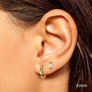4mm 14K yellow gold baguette diamond stud worn in lobe piercing paired with a chunky gold hoop