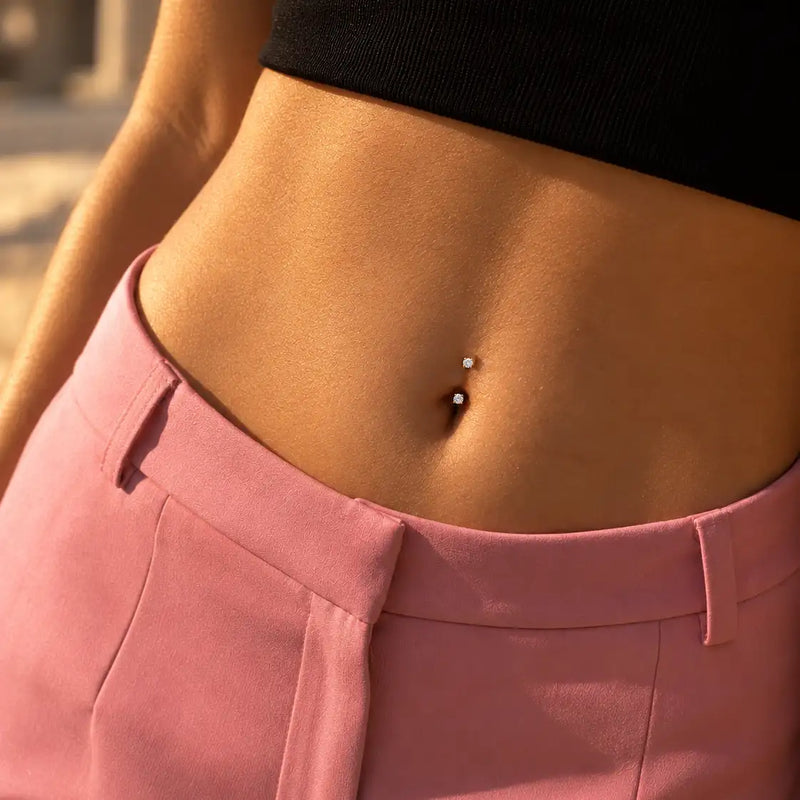 Model wearing a 3mm prong-set curved barbell in a belly button piercing - two round stones in 14k gold, available with diamond or cubic zirconia