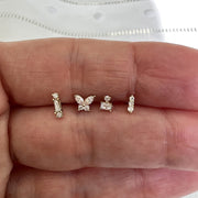 Four 14k gold diamond threadless stud ends held in hand for size comparison and scale reference