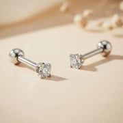 Pair of white gold cartilage studs with diamonds on a beige background