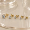 High-set diamond studs in various sizes displayed on a glass surface