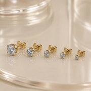 High-set diamond studs in various sizes displayed on a glass surface