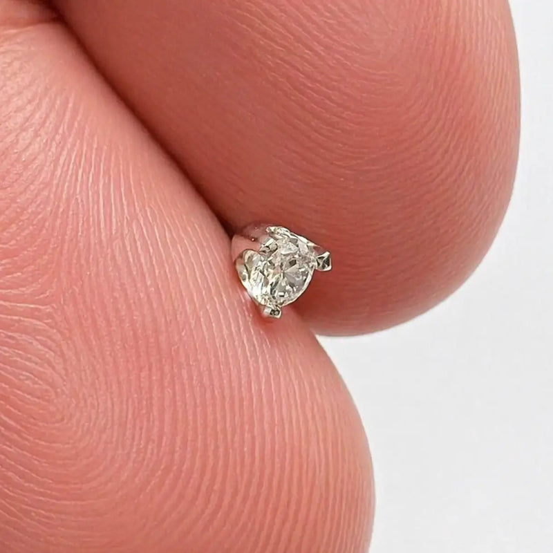 Close-up of 3mm VS1 diamond in 3-prong white gold setting resting on fingertip, showing tiny scale