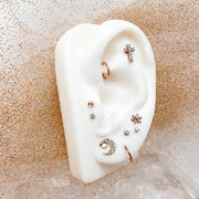 Diamond moon and star labret stud on white ear form styled in rose gold piercing cluster display
