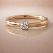 14K rose gold diamond side-set seam ring hoop with prong-set round diamond, on reflective surface
