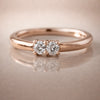 14K rose gold two-diamond seam ring hoop with prong-set VS1 diamonds, front view on reflective surface