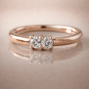 14K rose gold two-diamond seam ring hoop with prong-set VS1 diamonds, front view on reflective surface