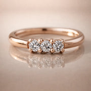 14k rose gold three-diamond seam ring hoop on reflective surface, front view