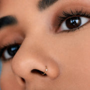 14K gold diamond side-set seam ring worn as nose ring piercing, close-up on model's face