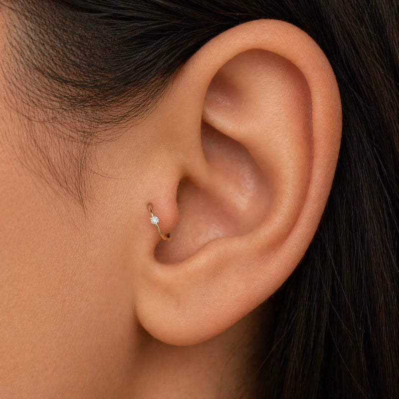 14K gold diamond seam ring hoop shown in tragus piercing on model's ear, close-up fit view