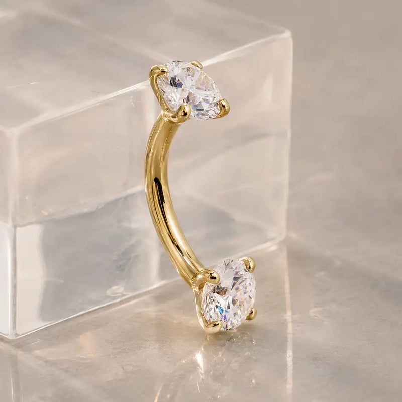Diamond curved barbell for navel, eyebrow, and rook piercings on a stand. 