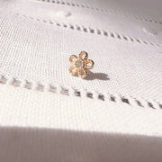 14k yellow gold dainty daisy flower push pin end shown on white linen fabric for size reference