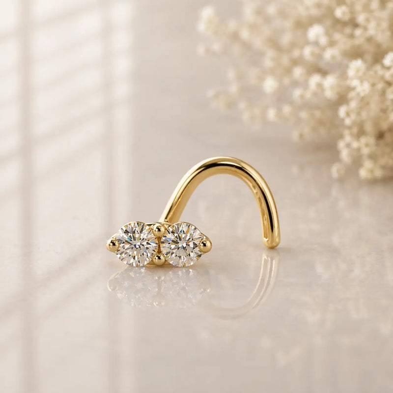 14K yellow gold double diamond nose ring twist, two prong-set round diamonds on reflective surface