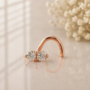 14K rose gold double diamond nose ring twist, two prong-set round diamonds on warm neutral surface
