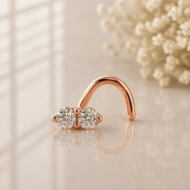14K rose gold double diamond nose ring twist, two prong-set round diamonds on warm neutral surface