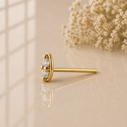 14K yellow gold double diamond nose stud straight post style, side profile on warm surface