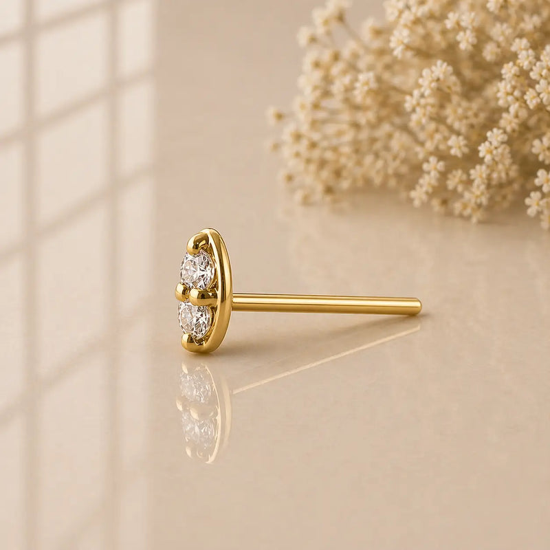 14K yellow gold double diamond nose stud straight post style, side profile on warm surface