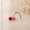 Ruby and pink sapphire, solid yellow gold nose twist, on a glass surface for a lifestyle photo.