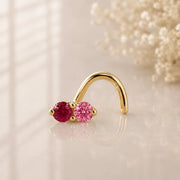 Ruby and pink sapphire, solid yellow gold nose twist, on a glass surface for a lifestyle photo.