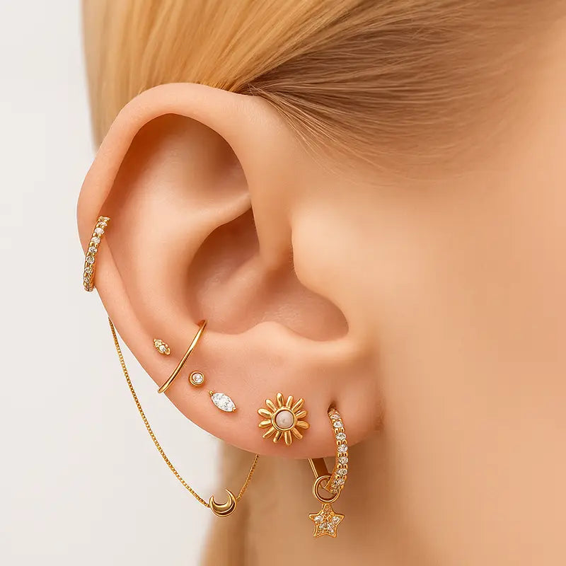 Close-up of an ear with gold earrings on a neutral background