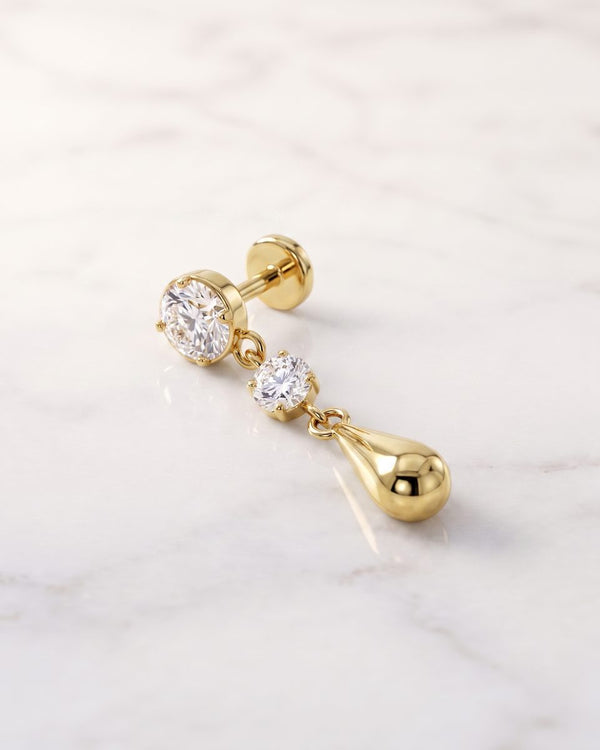 Dangle earrings - 14k yellow gold Brilliant Dew Drop earring with two bezel-set diamonds and a gold teardrop on white marble