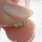 14k gold baguette and round diamond push pin end pinched between fingers for actual size reference