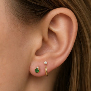 model wearing emerald and diamond stud Flat back, and a Solid gold hoop.