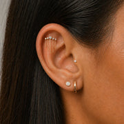 Model wearing a diamond climber flat back earring with chain dangles and a hoop and diamond studs.