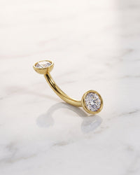 Diamond eyebrow jewelry - 14k yellow gold diamond bezel-set curved barbell on white marble