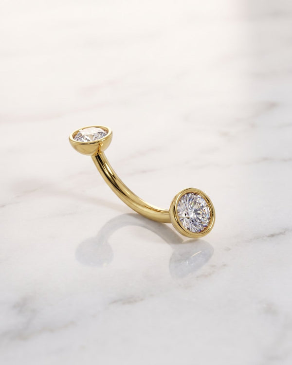 Diamond eyebrow jewelry - 14k yellow gold diamond bezel-set curved barbell on white marble