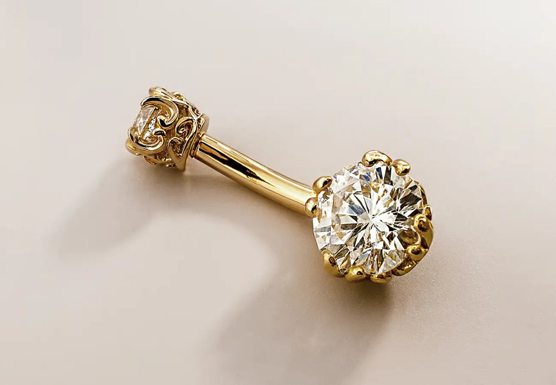 Gold belly button ring with a large diamond on a beige background