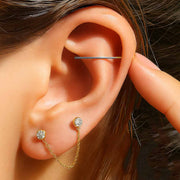 Insertion tool being used in a helix piercing on a model, with gold CZ chain connector studs in lobe