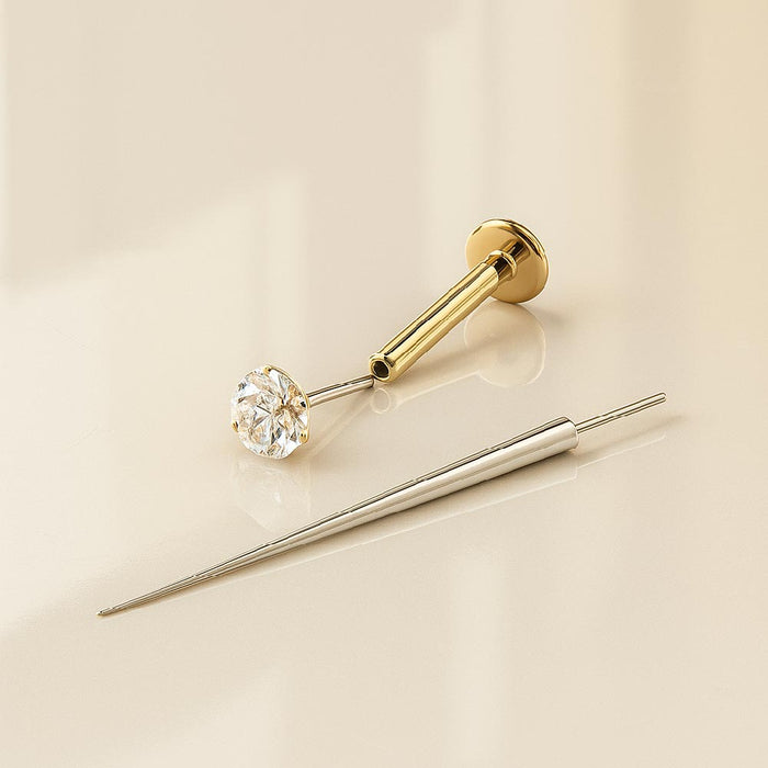 Flat back earring insertion tool beside a gold CZ flat back stud, showing tool and jewelry separately