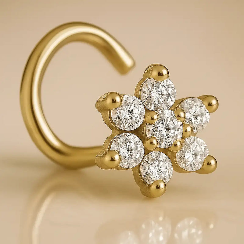 14K yellow gold diamond flower nose ring twist style, angled close-up on warm beige surface with reflection