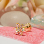 14k rose gold diamond flower flat back labret resting on pink surface with soft floral backdrop