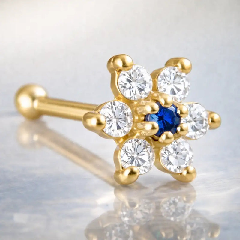 14K yellow gold flower nose bone with deep blue sapphire CZ center and clear CZ petals, angled view