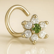 14K yellow gold CZ flower nose ring twist with green center CZ, angled close-up on warm background