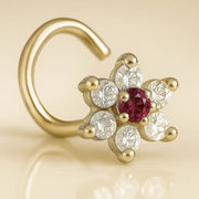 14K yellow gold CZ flower nose ring twist with ruby-red center CZ, angled view on beige background