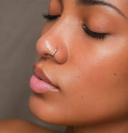 14K gold four-diamond seam ring hoop worn in a nose piercing, side profile view
