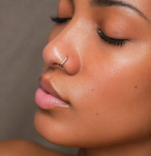 14K gold four-diamond seam ring hoop worn in a nose piercing, side profile view