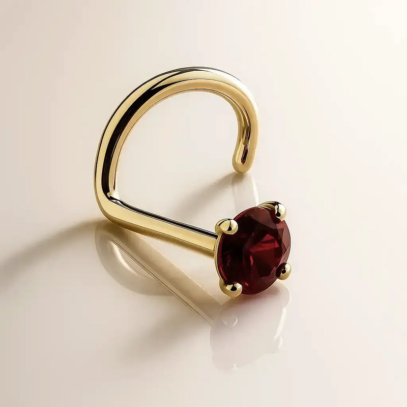 14K yellow gold garnet nose ring twist style with deep red round stone in four-prong setting, angled view
